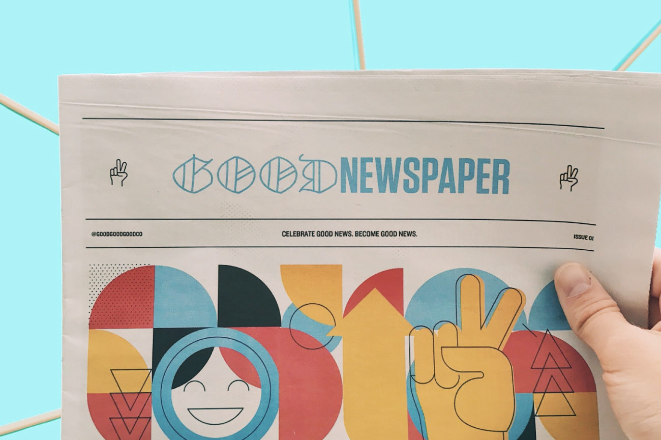 Giornale intitolato Good News tenuto in mano su uno sfondo colorato turchese